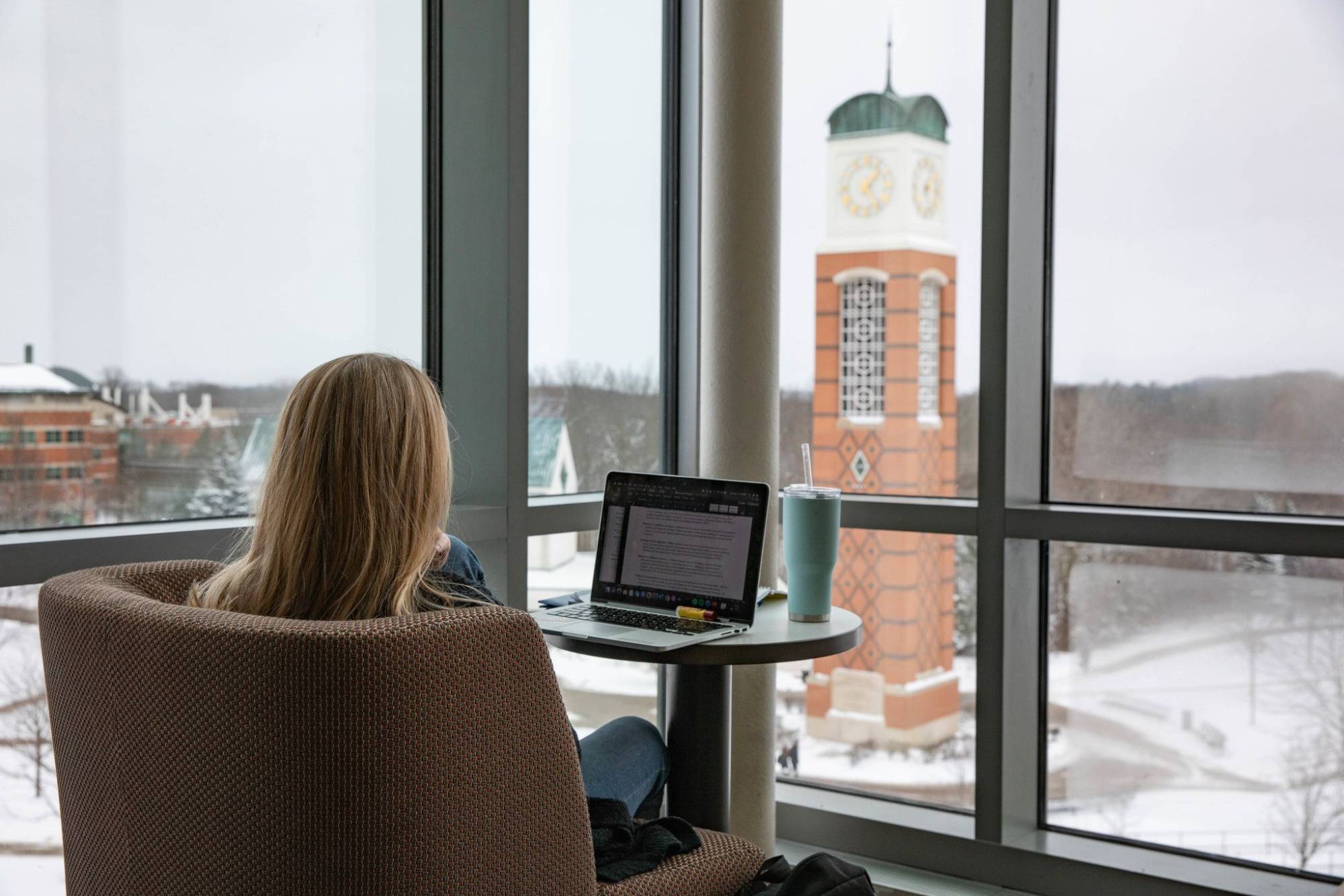 photo of student looking at computer with clock tower in the background
